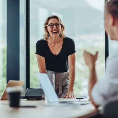 Businesswoman,Standing,At,Conference,Table,And,Laughing.,Female,Professional,Smiling