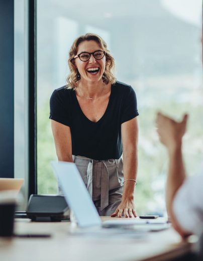 Businesswoman,Standing,At,Conference,Table,And,Laughing.,Female,Professional,Smiling